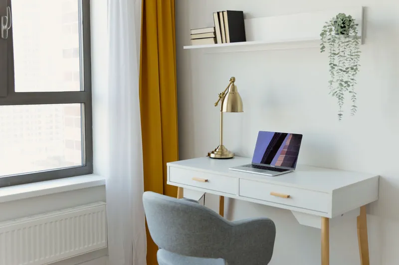 Minimalist home office workspace with laptop on white desk by window
